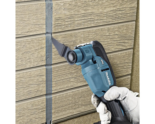 Makita Multifunktionsgeschier beim Ewechhuele vun Dichtstoff tëscht Wandpaneelen mat Holzstruktur.