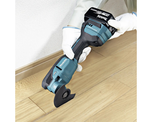 Makita Akku-Multifunktionswerkzeug mit 18 Volt Akku beim Schneiden von Holzboden.