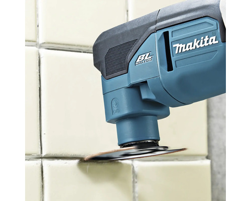 Makita Akku-Multitool mit bürstenlosem Motor beim Entfernen von Fugenmaterial zwischen Wandfliesen mit einem runden Werkzeugaufsatz.
