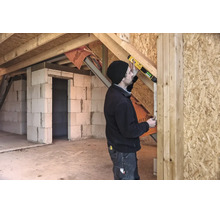Artisan utilisant un niveau à bulle numérique avec STABILA Logo sur une poutre en bois dans un bâtiment brut avec parois en béton cellulaire.