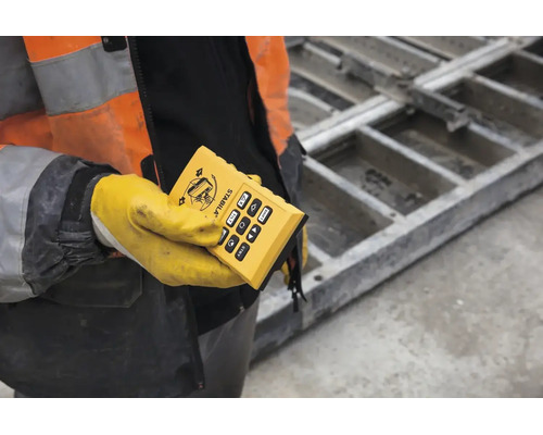 Télécommande Stabila pour laser de chantier, tenue par une personne en tenue de protection sur un chantier.