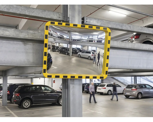Konvexer Sicherheitsspiegel mit gelb-schwarz gestreiftem Rahmen in einer hellen Parkgarage zur Verbesserung der Sichtbarkeit.