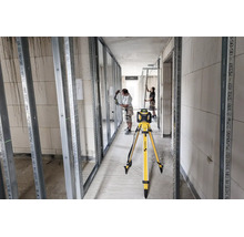 Laser rotatif Stabila sur trépied sur un chantier d aménagement intérieur avec des profilés métalliques et deux ouvriers.