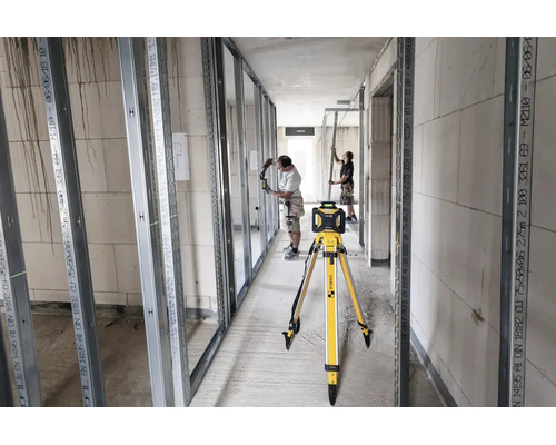 Laser rotatif Stabila sur trépied sur un chantier d aménagement intérieur avec des profilés métalliques et deux ouvriers.