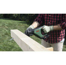Une personne coupe une poutre en bois avec une scie sabre sans fil Bosch dans un jardin.