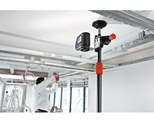 Bosch Baustativ mit montiertem Kreuzlinienlaser bei der Arbeit in einem Innenraum mit Metallständerprofilen an der Decke.