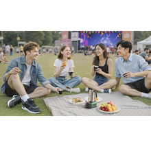 Vier Personen beim Picknick auf einer Wiese mit einer mobilen Bosch Kaffeemaschine und Snacks bei einer Außenveranstaltung.