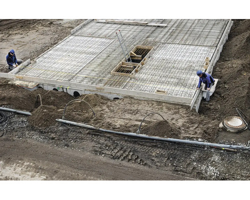 Chantier avec une dalle de béton, des armatures en acier et des ouvriers du bâtiment lors de la création d une fondation.
