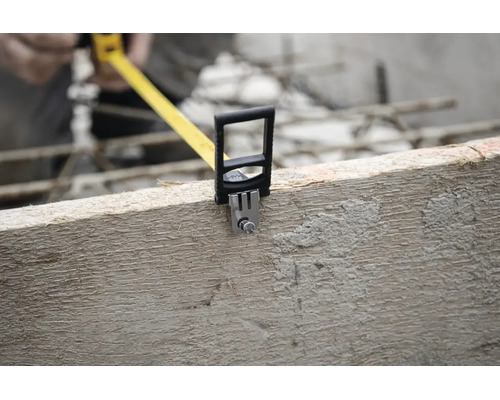 Mètre ruban jaune fixé sur une poutre en bois sur un chantier.