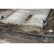 Chantier avec une dalle de béton, des armatures en acier et des ouvriers du bâtiment lors de la création d une fondation.