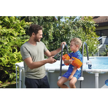 Homme gonflant les brassards d'un enfant avec une pompe à air sans fil près d'une piscine de jardin.
