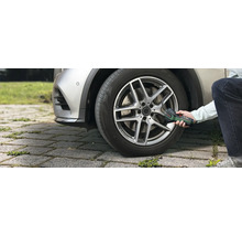 Une personne gonfle un pneu de voiture en extérieur à l'aide de la pompe à air comprimé sans fil Bosch EasyPump.