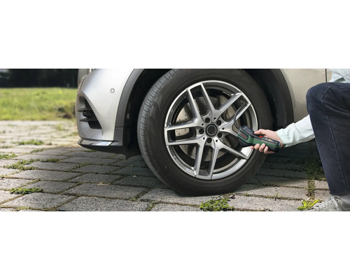 Une personne gonfle un pneu de voiture en extérieur à l'aide de la pompe à air comprimé sans fil Bosch EasyPump.