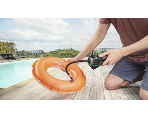 Une personne utilise une pompe à air sans fil Bosch pour gonfler une bouée orange au bord d'une piscine.