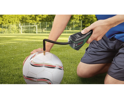 Pompe à air sans fil Bosch gonflant un ballon de football sur un terrain en herbe.