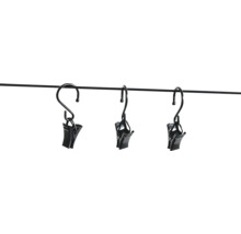 Trois pinces à rideaux noires avec crochets en métal, suspendues à une fine barre.