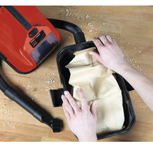 Insertion d'un sac à poussière en papier dans un aspirateur eau et poussière Einhell 18 Volt Power X-Change sur un établi.
