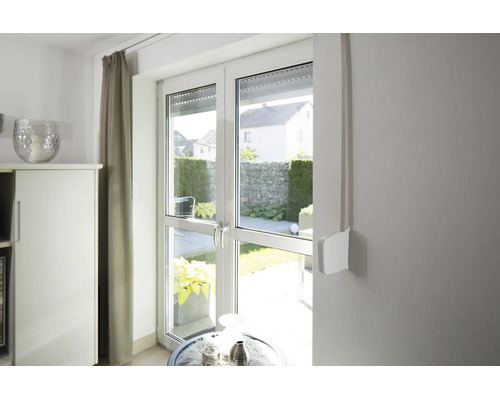 Aufputz-Gurtwickler fir Rollläden montéiert un enger Mauer niewent enger Terrassendier aus Glas an engem hellen Raum.