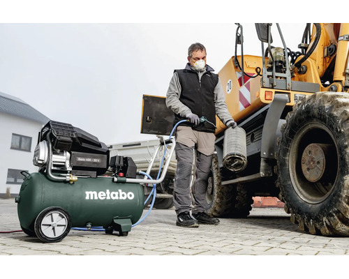 Une personne nettoie un filtre à air d'un engin de chantier avec un compresseur Metabo Basic 400-50 V.