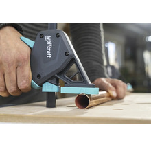 Wolfcraft Einhandzwinge Pro fixiert ein Kupferrohr auf einer hölzernen Werkbank bei der Metallbearbeitung.