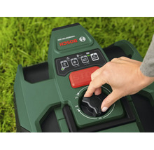 Hand bedient den Drehknopf zur Schnitthöheneinstellung an einem Bosch Mähroboter mit Bedienfeld, Stopp-Taste und Bosch Logo.