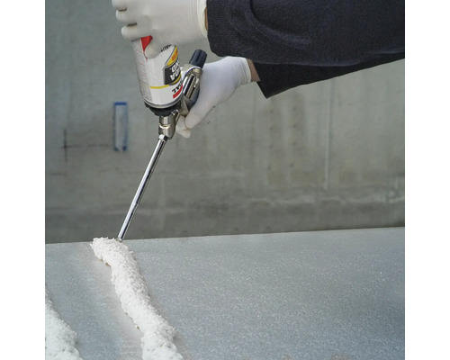 Une personne applique de la mousse polyuréthane sur une plaque avec un pistolet à mousse.