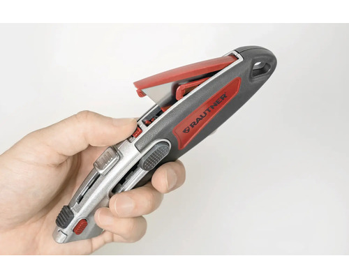 Main tenant un cutter Rautner avec un compartiment de rangement pour lames ouvert.