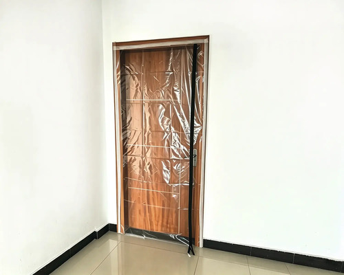 Porte anti-poussière avec fermeture à glissière pour les rénovations, montée sur un cadre de porte en bois.