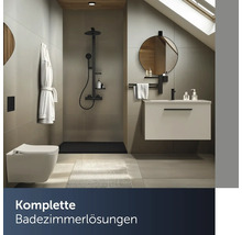 Modernes Badezimmer mit ebenerdiger Dusche, Wand-WC, Waschtisch mit Unterschrank und rundem Spiegel unter einer Dachschräge.