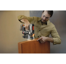 Homme utilisant un cloueur sans fil Worx avec éclairage LED sur un morceau de bois.