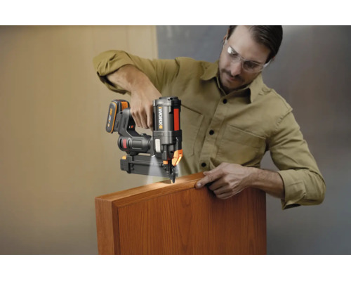 Homme utilisant un cloueur sans fil Worx avec éclairage LED sur un morceau de bois.