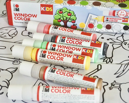 Marabu Kids Window Color Set mit sechs Malstiften auf einer Malvorlage vor der Verpackung.