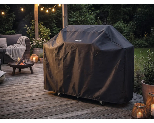 Housse de protection Tenneker pour barbecue sur une terrasse en bois à côté d'un brasero allumé et de meubles de jardin au crépuscule.