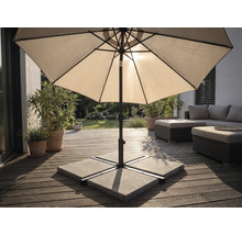 Parasol sur une terrasse en bois avec un socle en plaques de béton, des meubles de jardin et des plantes dans un espace extérieur lumineux.
