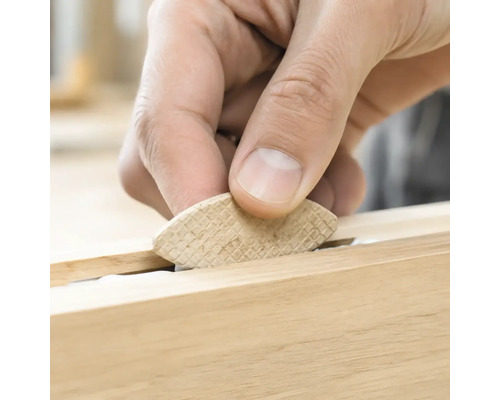 Une main insère une lamelle d assemblage en bois dans une rainure pour l assemblage du bois.