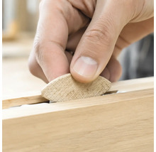 Une main insère une lamelle d assemblage en bois dans une rainure pour l assemblage du bois.