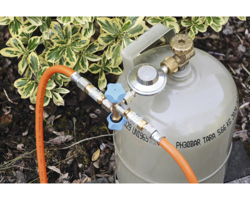 Bouteille de gaz avec régulateur de pression, vanne de dérivation double avec poignées et deux tuyaux de gaz raccordés à l'extérieur.