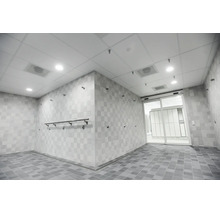 Espace de douche commune moderne et spacieux avec carrelage mural et de sol clair et une porte coulissante en verre menant au vestiaire.