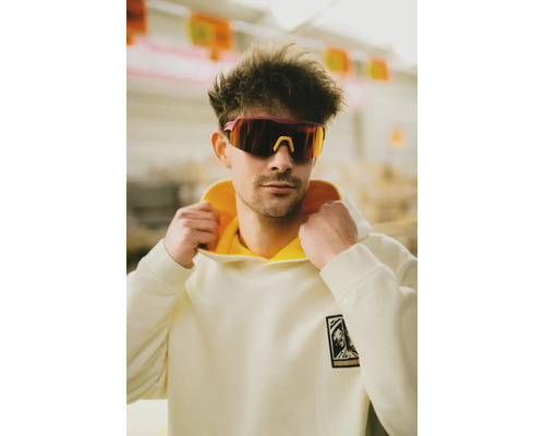 Ein Mann trägt einen cremefarbenen Hornbach Kapuzenpullover mit gelbem Innenfutter und eine sportliche Schutzbrille.