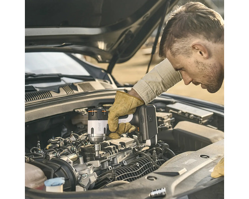 Un homme utilisant une boulonneuse à chocs sans fil Litheli pour travailler sur un moteur de voiture avec le capot ouvert.