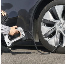Une personne utilise un compresseur d'air électrique portable pour gonfler un pneu de voiture.