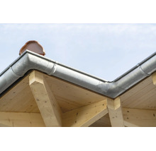 Gouttière en zinc montée sur une structure de toit en bois avec des tuiles visibles.