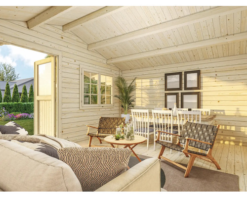 Intérieur lumineux d'un abri de jardin en bois clair avec canapé, fauteuils, table à manger et vue sur le jardin par une porte ouverte.