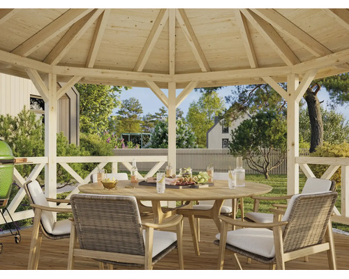Pavillon de jardin en bois avec un ensemble composé d'une table ronde en bois et de chaises tressées dans un grand jardin lumineux.