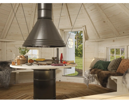 Intérieur d'un kota grill en bois avec barbecue central, hotte, table ronde, bancs et vue sur l'extérieur.