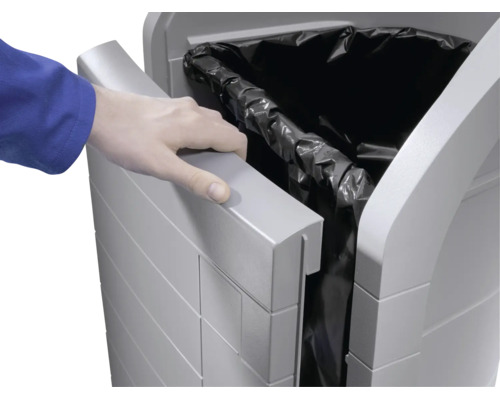 Une main ouvre une poubelle en plastique grise avec un sac poubelle noir inséré.