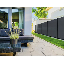 Clôture brise-vue moderne en anthracite sur une terrasse organisée avec dalles grises, meubles de jardin en résine tressée et pelouse.