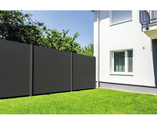 Clôture brise-vue moderne composée de panneaux foncés dans un jardin sur une pelouse à côté d'une maison.