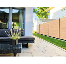 Terrasse moderne avec des dalles gris clair, meubles de jardin en polyrotin foncé et clôture brise-vue aspect bois.