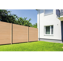 Clôture brise-vue moderne en bois composite installée sur une pelouse à côté d'un mur de maison blanc avec fenêtre.